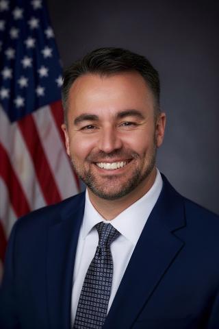 Headshot of Luiz A. Santos in front of American flag